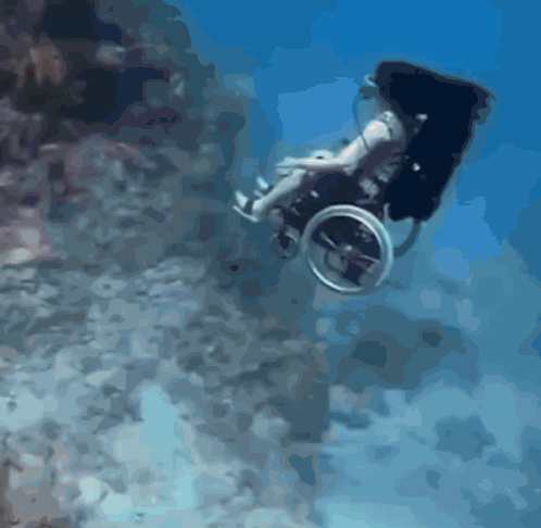 A Man In A Wheelchair Is Swimming Underwater GIF