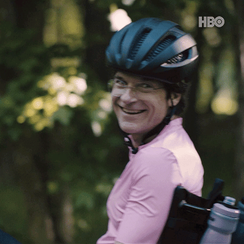 A Man In A Wheelchair Wearing A Helmet And A Pink Shirt With Hbo Written On The Bottom Right GIF