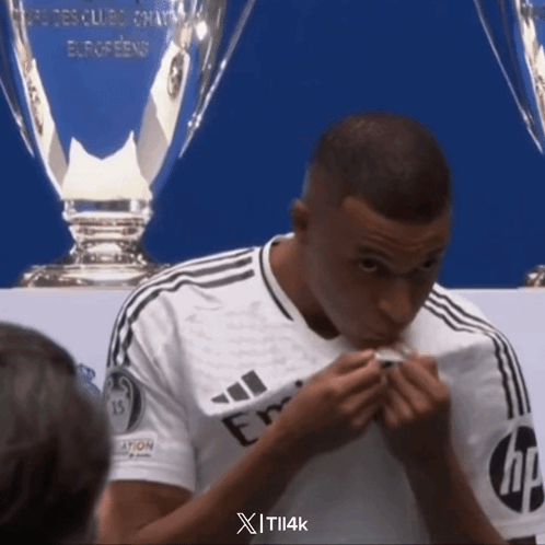 A Man In A White Adidas Shirt Is Eating Something GIF