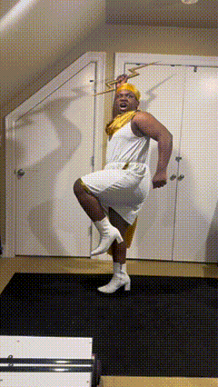 A Man In A White Dress Holds A Trumpet In His Hand GIF