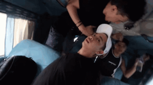 A Man In A White Hat Is Laying On A Blue Couch . GIF