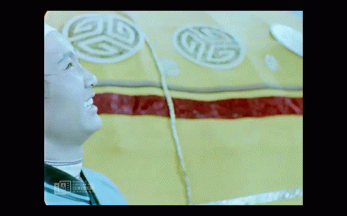 A Man In A White Hat Is Smiling In Front Of A Yellow And Red Item With A G On It GIF