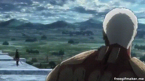 A Man In A White Hat Is Standing In Front Of A Mountain Range . GIF