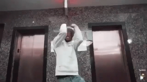Man In White Hoodie In Front Of Elevators GIF