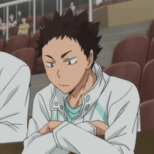 A Man In A White Jacket And A Blue Shirt Is Sitting In A Stadium GIF