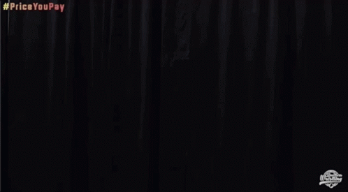 A Man In A White Jacket And Gold Shorts Is Standing In Front Of A Black Curtain And Screaming . GIF