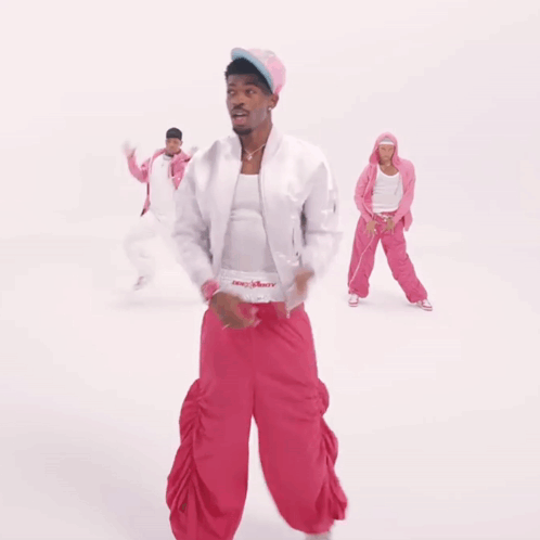 A Man In A White Jacket And Pink Pants Is Dancing With Two Other People GIF