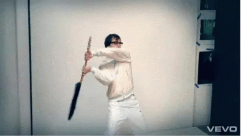 A Man In A White Jacket Is Holding An Umbrella In Front Of A Vevo Logo . GIF