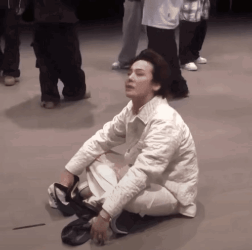 A Man In A White Jacket Is Kneeling Down On The Floor GIF