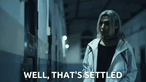 a man in a white jacket is standing in a dark hallway with the words well that 's settled below him