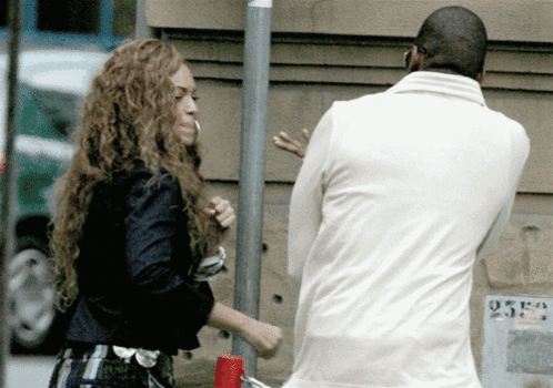 A Man In A White Jacket Stands Next To A Woman In A Black Jacket GIF