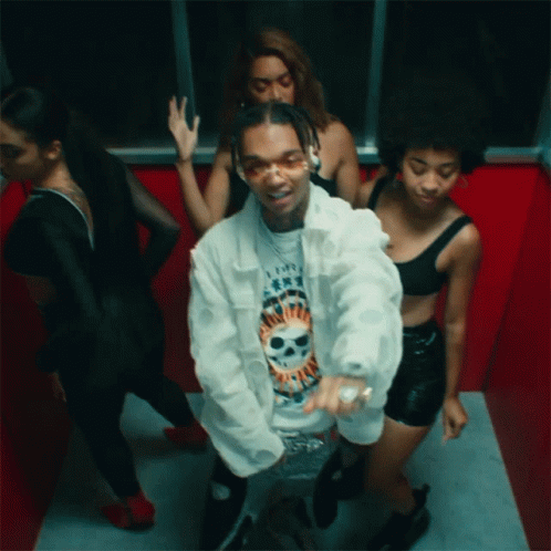 A Man In A White Jacket With A Skull On His Shirt Is Surrounded By Women GIF