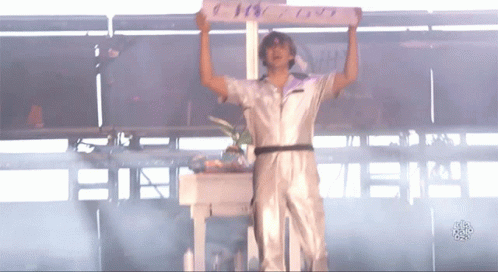 A Man In A White Jumpsuit Is Holding Up A Sign That Says ' I Love You ' On It GIF