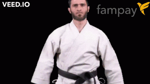 A Man In A White Karate Uniform With A Black Belt Is Standing In Front Of A Fampay Logo GIF