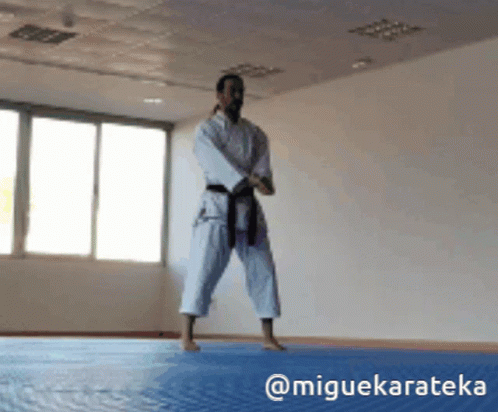 A Man In A White Karate Uniform With A Black Belt GIF