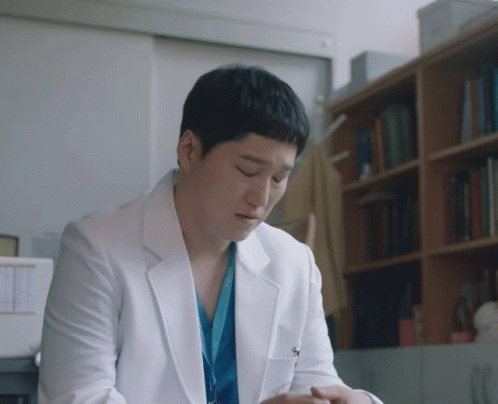 A Man In A White Lab Coat Has A Lanyard Around His Neck That Says ' Surgical ' On It GIF