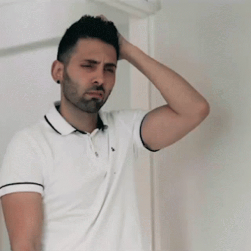 A Man In A White Polo Shirt Holds His Hand To His Forehead GIF
