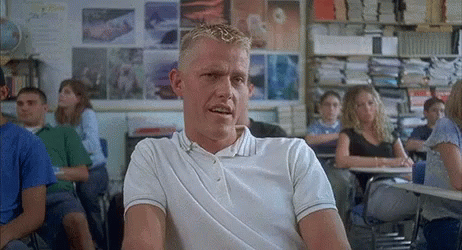 A Man In A White Polo Shirt Sits In A Classroom With Other Students GIF