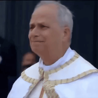 A Man In A White Robe And Gold Trim Is Smiling GIF