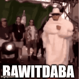 A Man In A White Robe And Hat Is Walking In Front Of A Crowd With The Words Rawitdaba Written On The Bottom . GIF