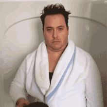 a man in a white robe is sitting in a bathtub .