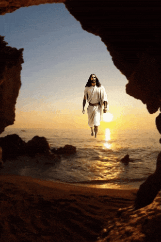 A Man In A White Robe Is Walking Out Of A Cave Into The Ocean GIF