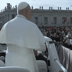 A Man In A White Robe Stands In Front Of A Large Crowd GIF