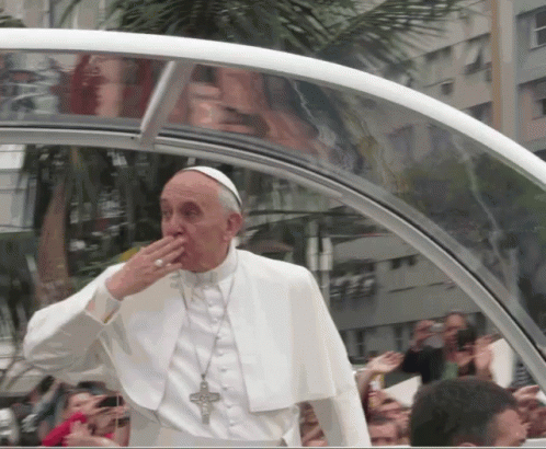 A Man In A White Robe With A Cross Around His Neck Is Covering His Mouth GIF