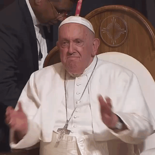 A Man In A White Robe With A Cross Necklace GIF
