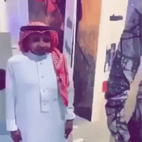 A Man In A White Shirt And A Red Scarf Is Standing Next To A Soldier In A Room . GIF