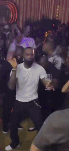 a man in a white shirt and black pants is dancing in a crowd