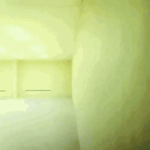 A Man In A White Shirt And Black Pants Is Running In A Room With Yellow Walls GIF