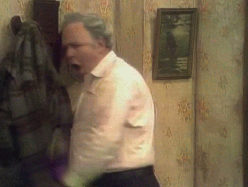a man in a white shirt and black pants is standing in a room with his mouth open .