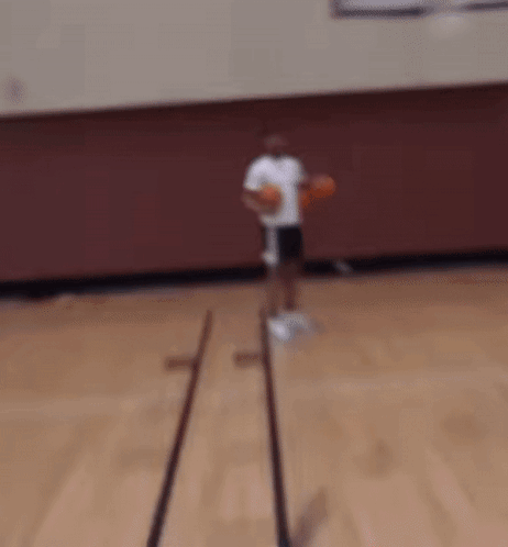A Man In A White Shirt And Black Shorts Is Holding Two Basketballs In His Hands GIF