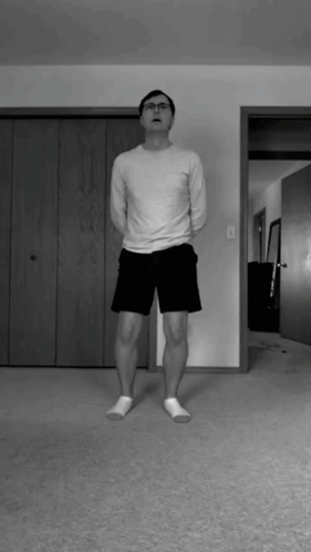 a man in a white shirt and black shorts is standing in a living room