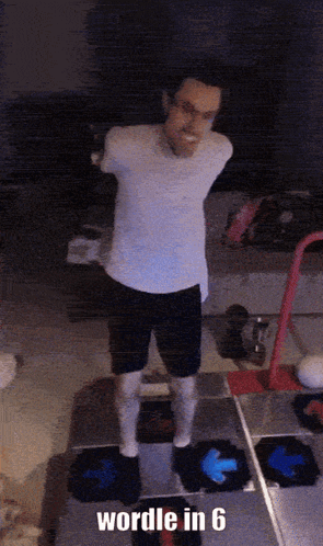 A Man In A White Shirt And Black Shorts Is Standing On A Dance Floor With The Words " Wordle In 6 " Below Him GIF