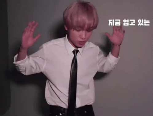 A Man In A White Shirt And Black Tie Is Dancing In Front Of A Wall With Chinese Writing On It GIF