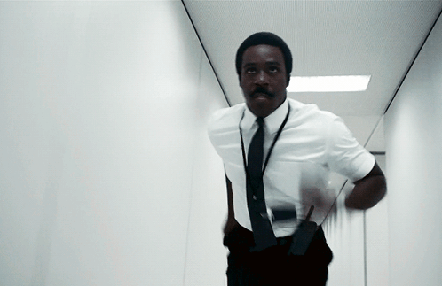 a man in a white shirt and black tie is running in a hallway