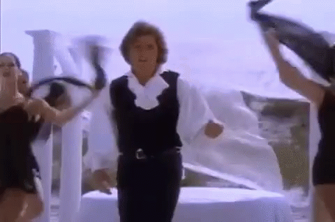 a man in a white shirt and black vest is dancing with two women .