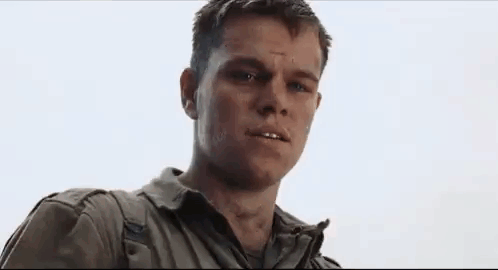 A Man In A White Shirt And Blue Jacket Is Looking At The Camera With A Serious Look On His Face . GIF