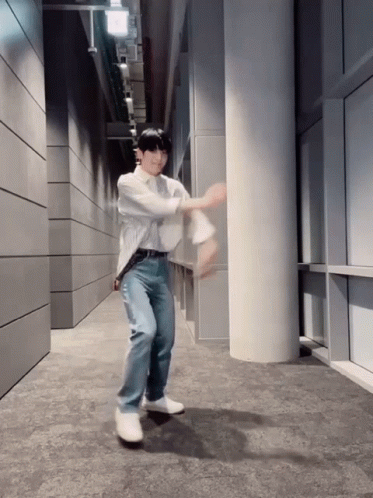 A Man In A White Shirt And Blue Jeans Is Dancing GIF