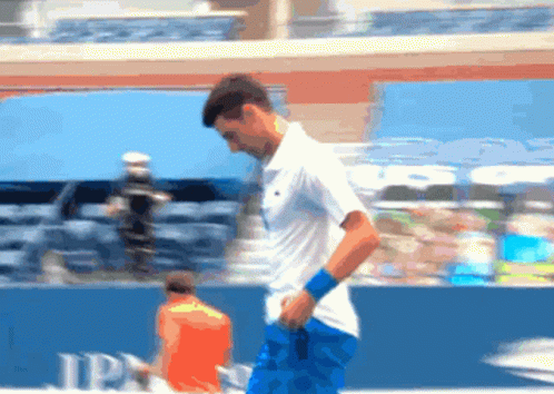 A Man In A White Shirt And Blue Shorts Is Walking On A Tennis Court In Front Of A Jp Morgan Sign GIF