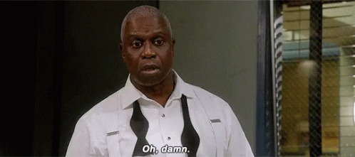 a man in a white shirt and bow tie is standing in front of a window and says `` oh , damn '' .