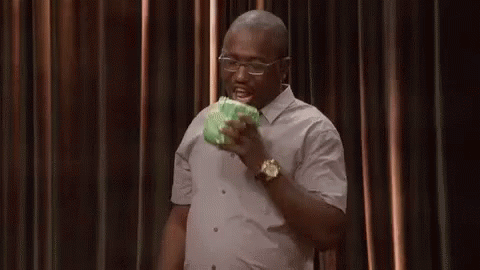 A Man In A White Shirt And Glasses Is Eating A Piece Of Cabbage . GIF