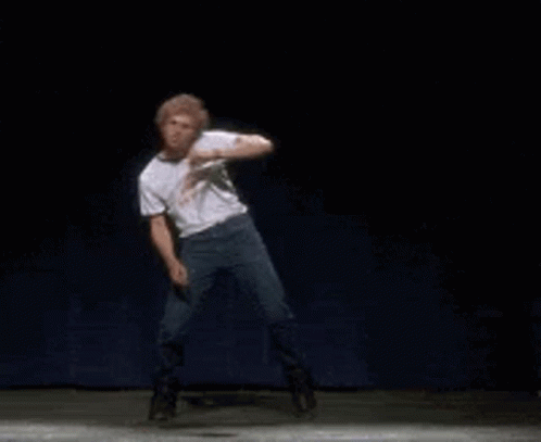 A Man In A White Shirt And Jeans Is Dancing On A Stage . GIF