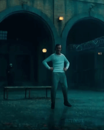 a man in a white shirt and jeans is jumping in the air in a dark room .