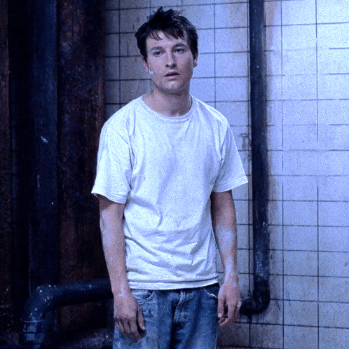 Man In White Shirt And Jeans Standing In Front Of Wall GIF