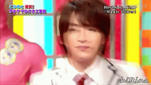 A Man In A White Shirt And Red Tie Is Talking Into A Microphone On A Colorful Background . GIF