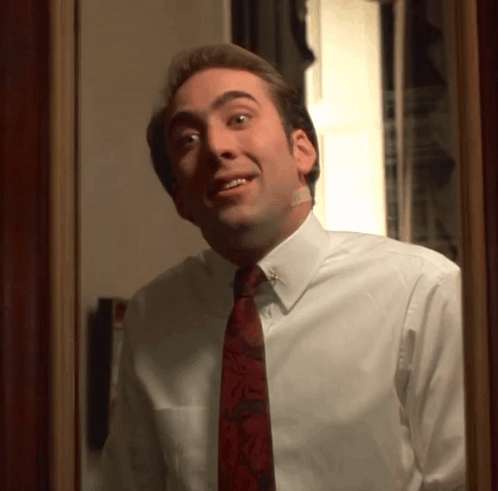 A Man In A White Shirt And Red Tie Looks At Himself In The Mirror GIF