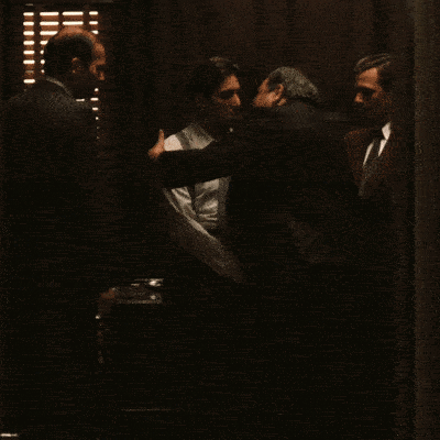 A Man In A White Shirt And Suspenders Is Shaking Hands With Another Man GIF